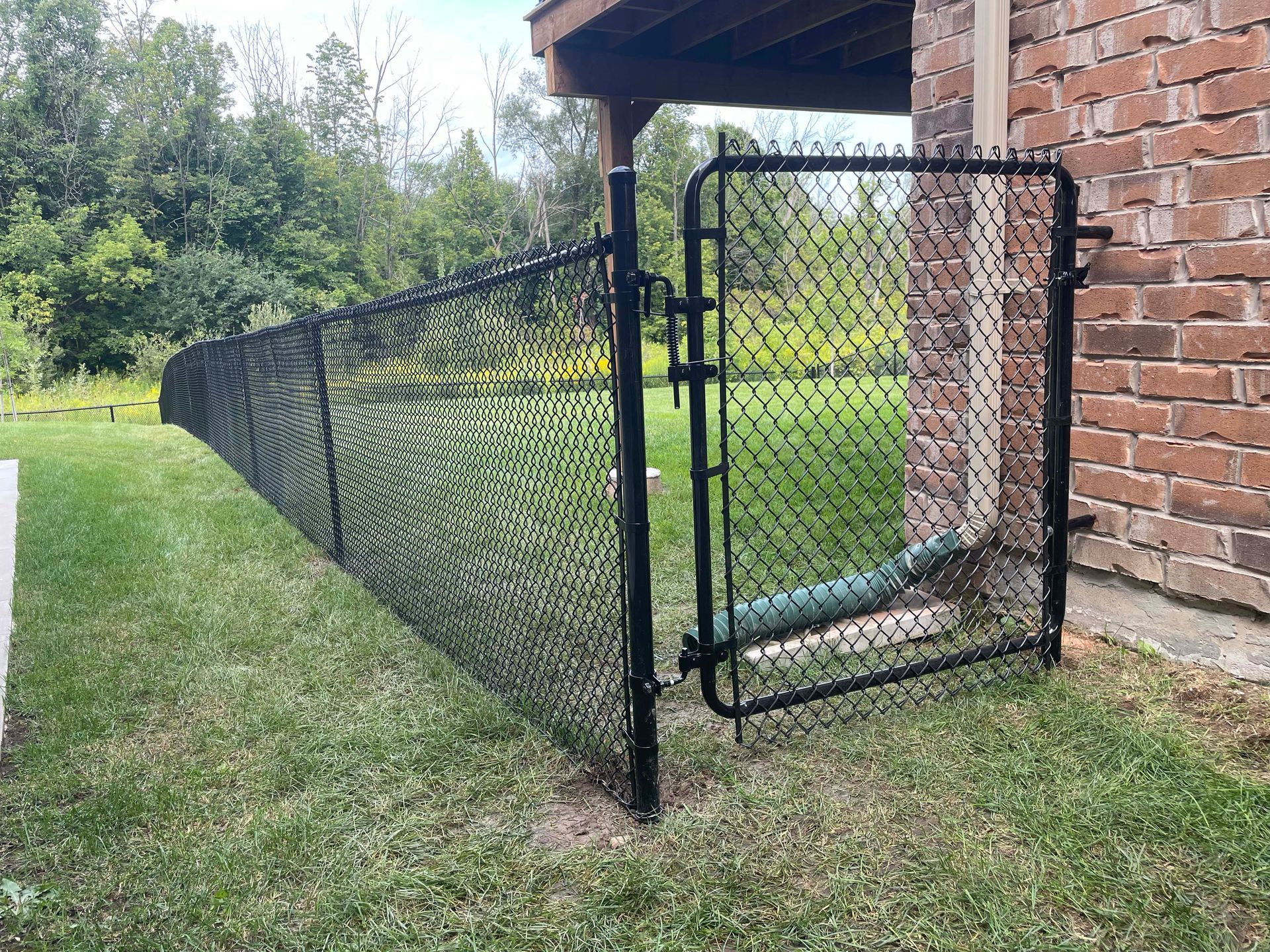 A chain link fence with a gate in front of a brick building.