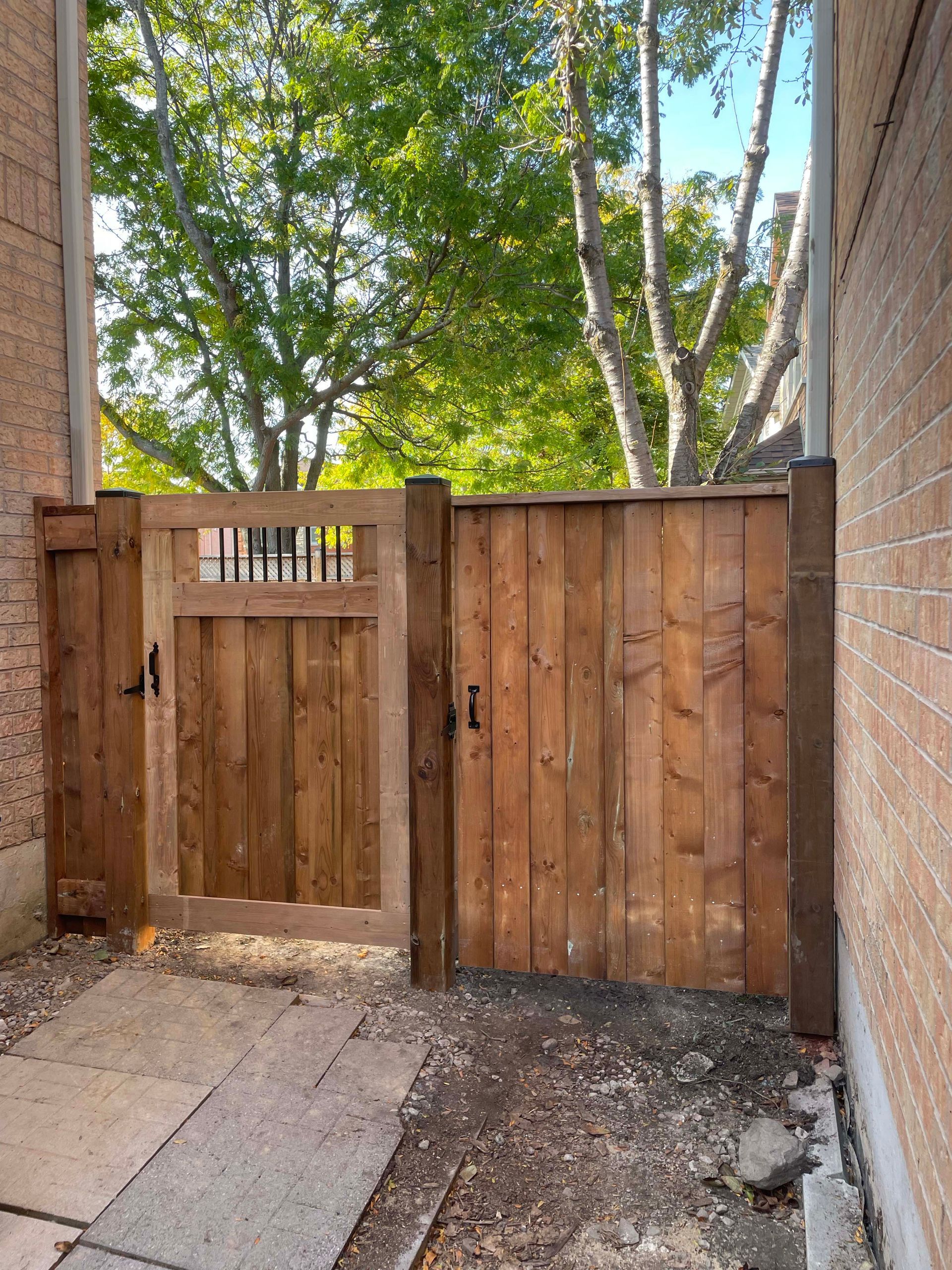 A wooden gate is sitting next to a brick wall.