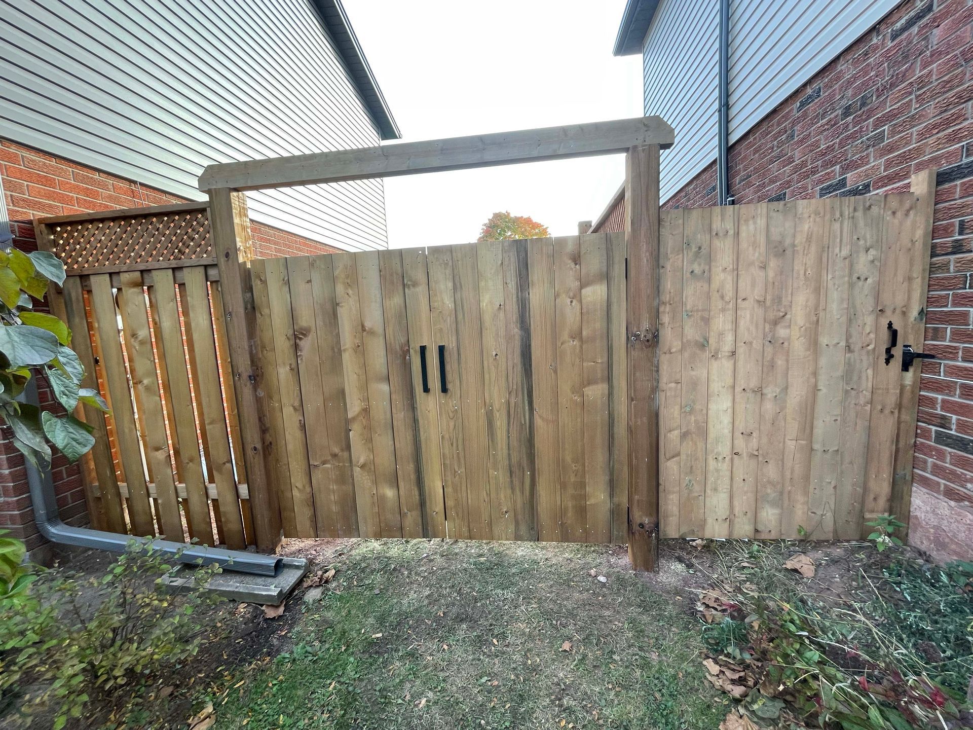 A wooden fence with a gate in front of a brick building.