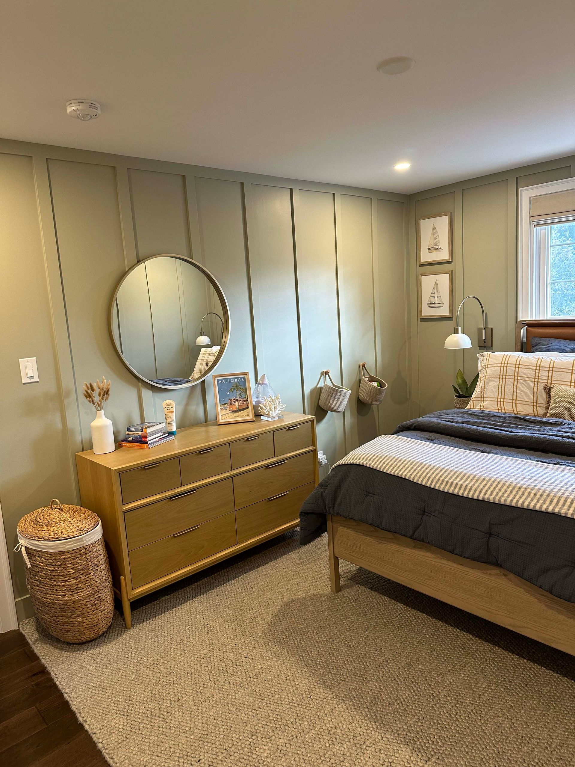 A bedroom with a bed , dresser , mirror and rug.
