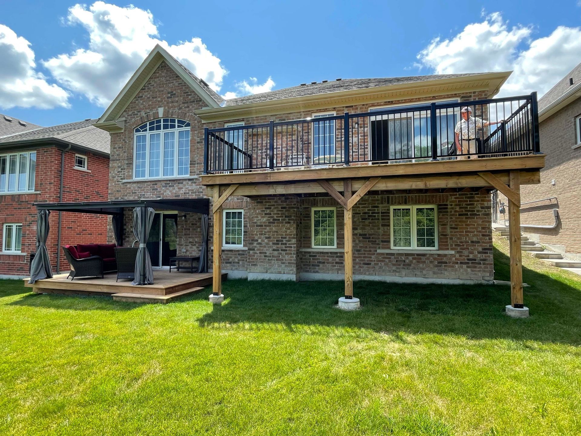 A large brick house with a large deck in the backyard.