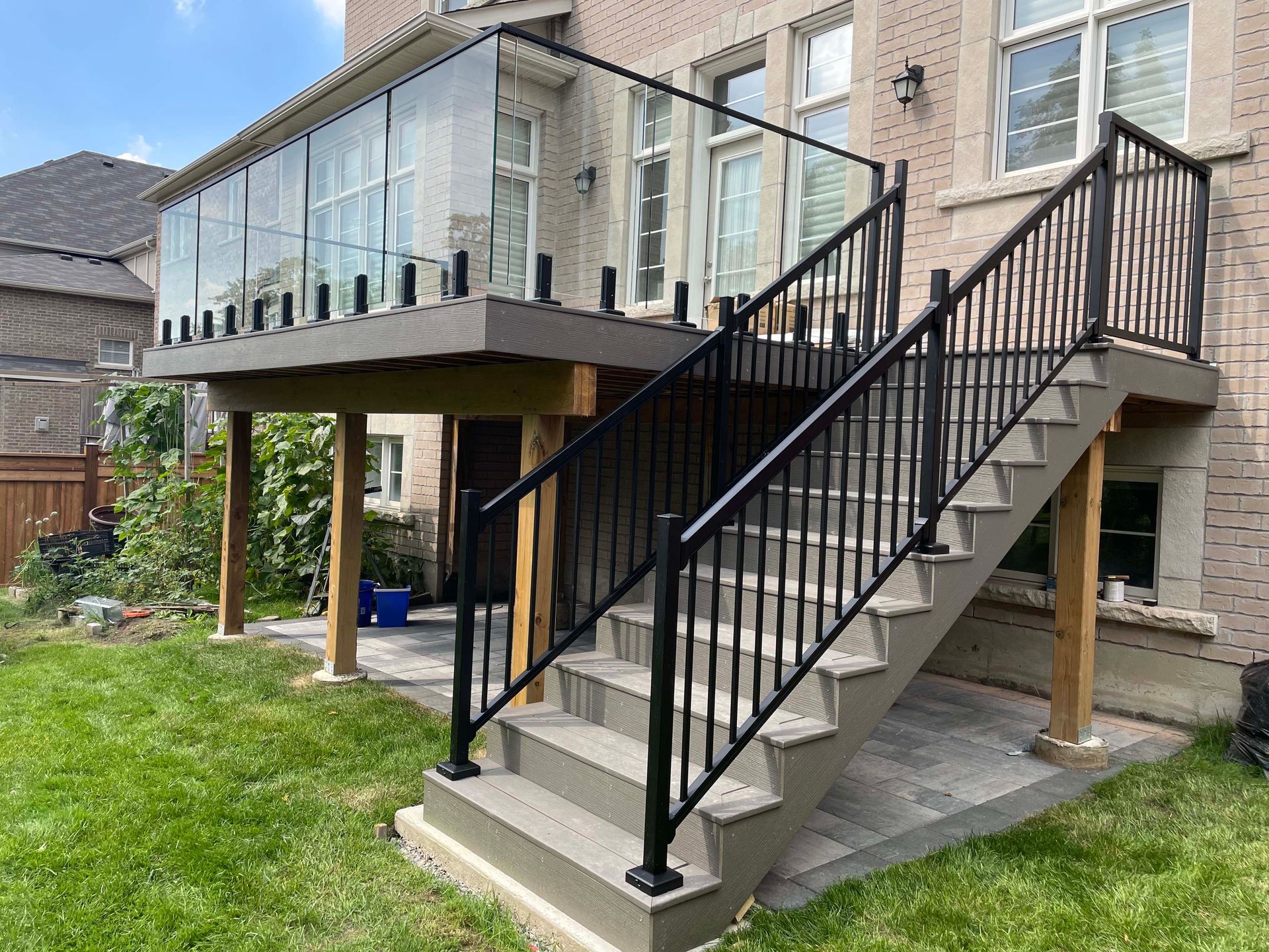 A deck with stairs leading up to it and a glass railing.