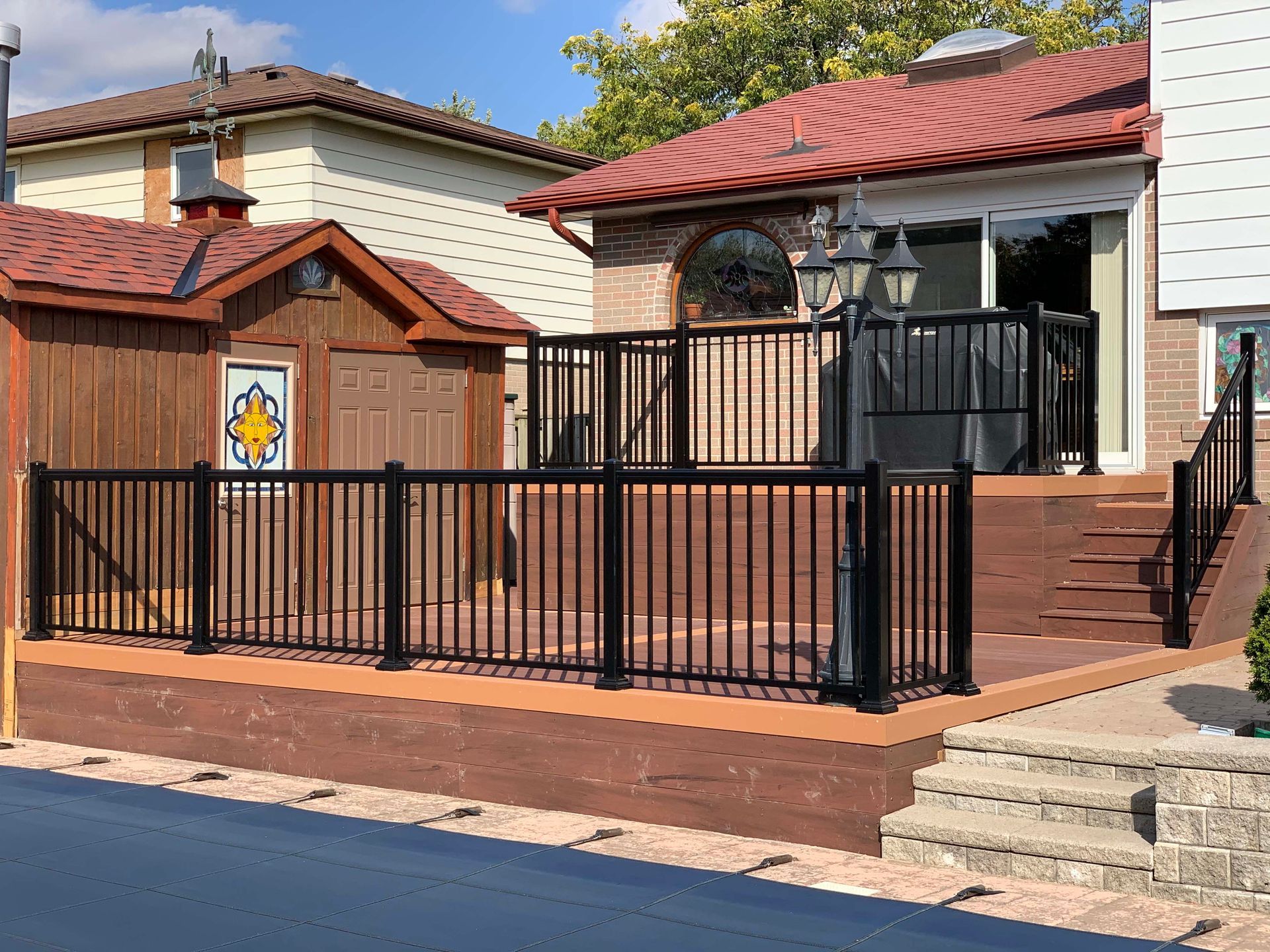 A deck with stairs and a black fence in front of a house.