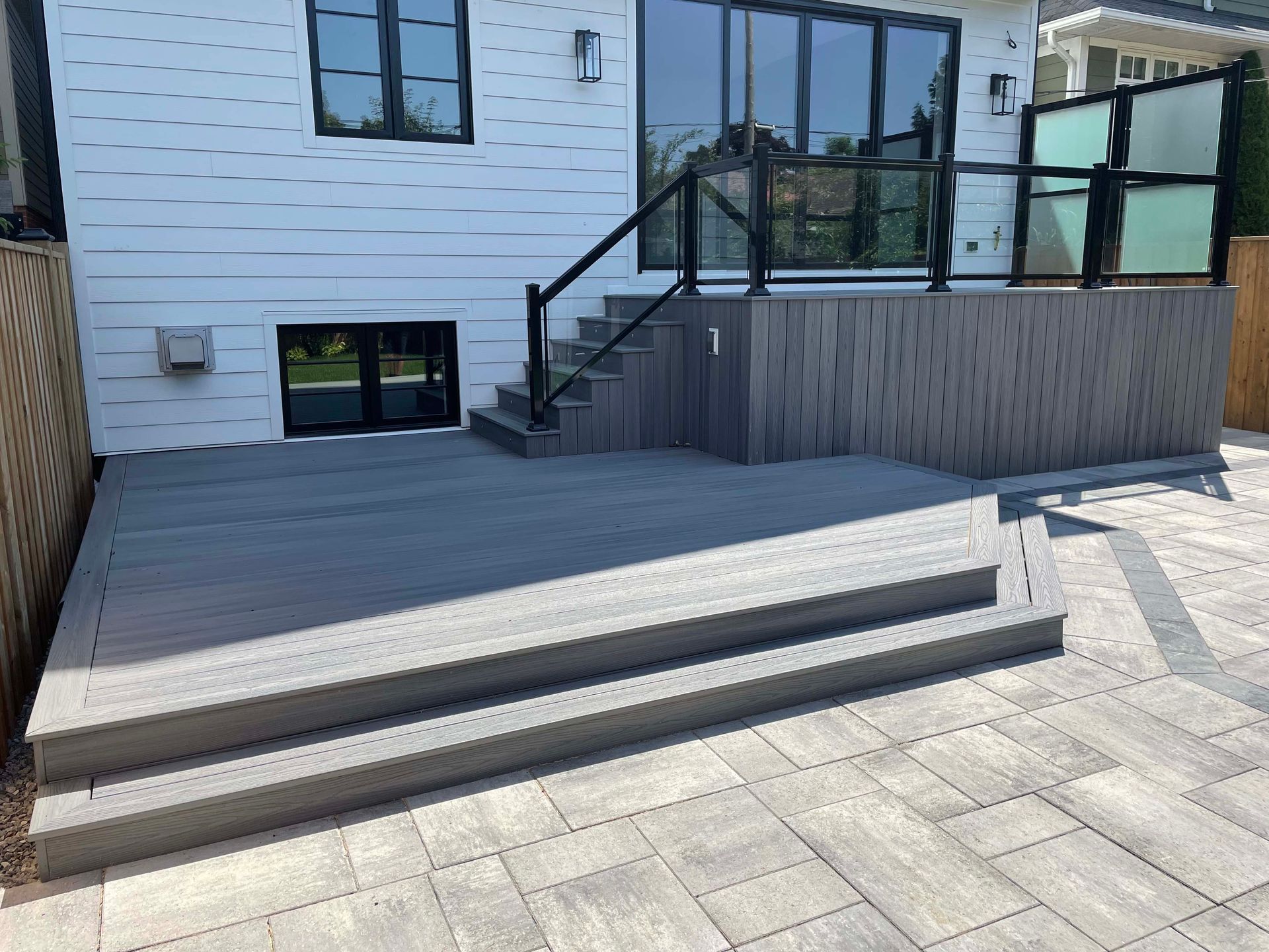 A patio with stairs and a deck in front of a house.