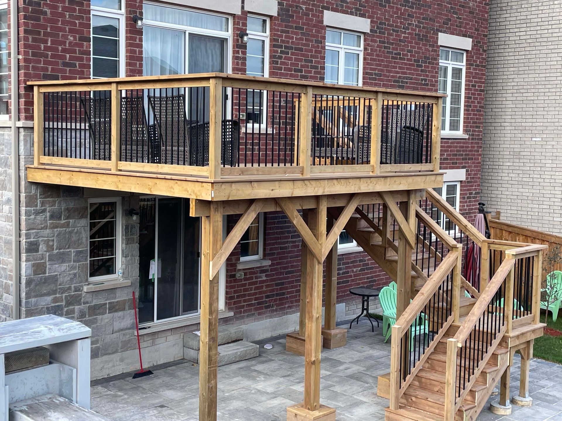 A wooden deck with stairs leading up to it is in front of a brick building.