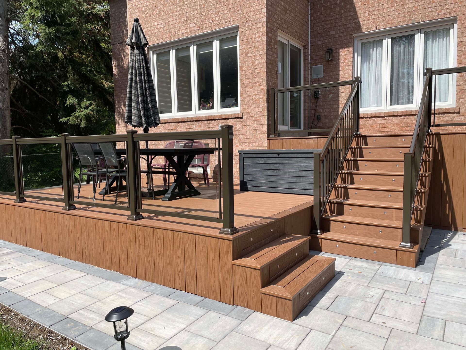 A wooden deck with stairs and a table and chairs on it in front of a house.