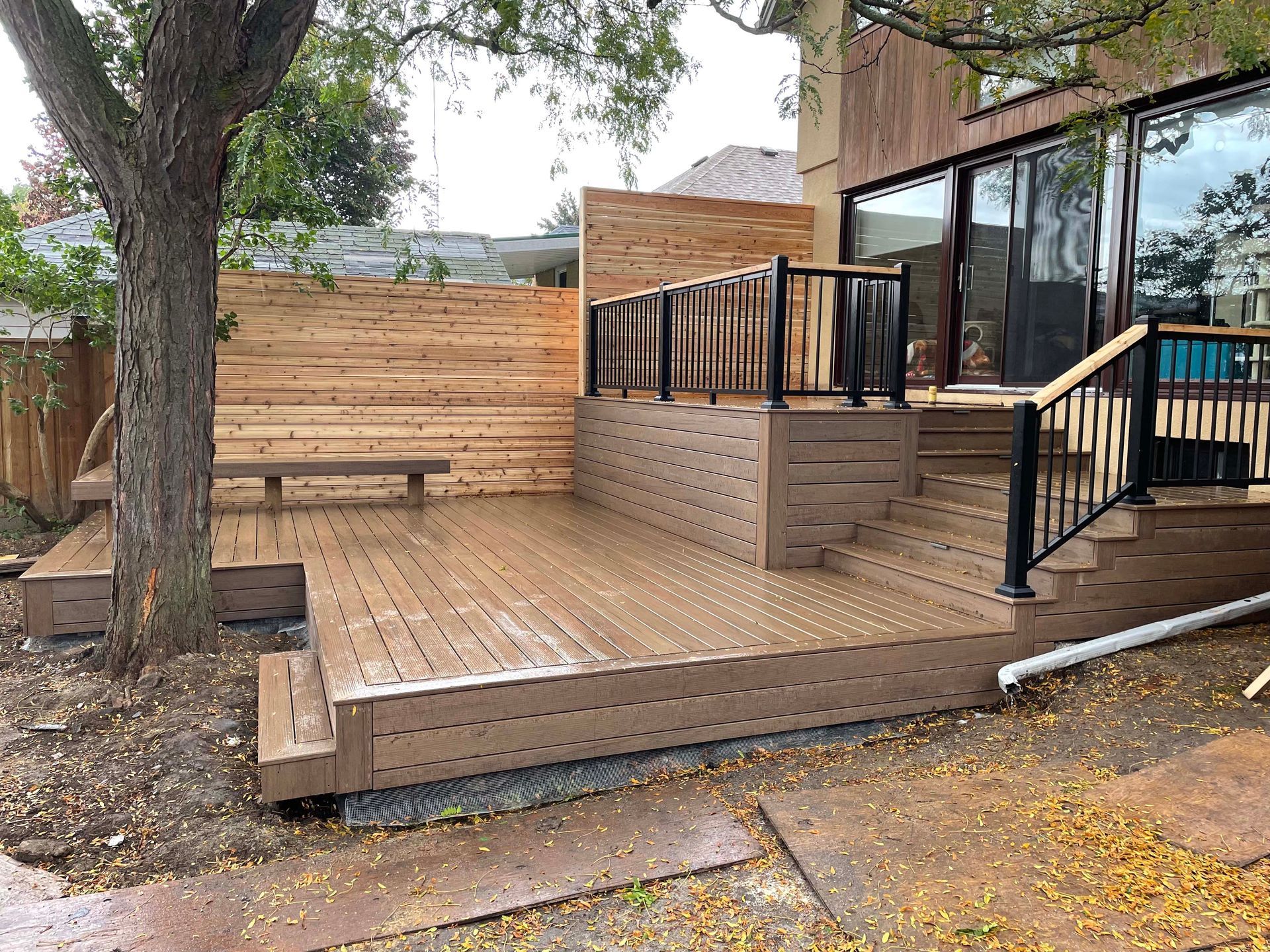 A wooden deck with stairs and a bench in front of a house.