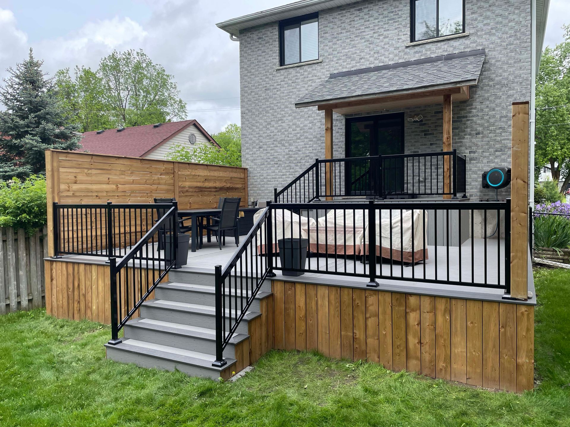 There is a deck with stairs leading up to it in the backyard of a house.