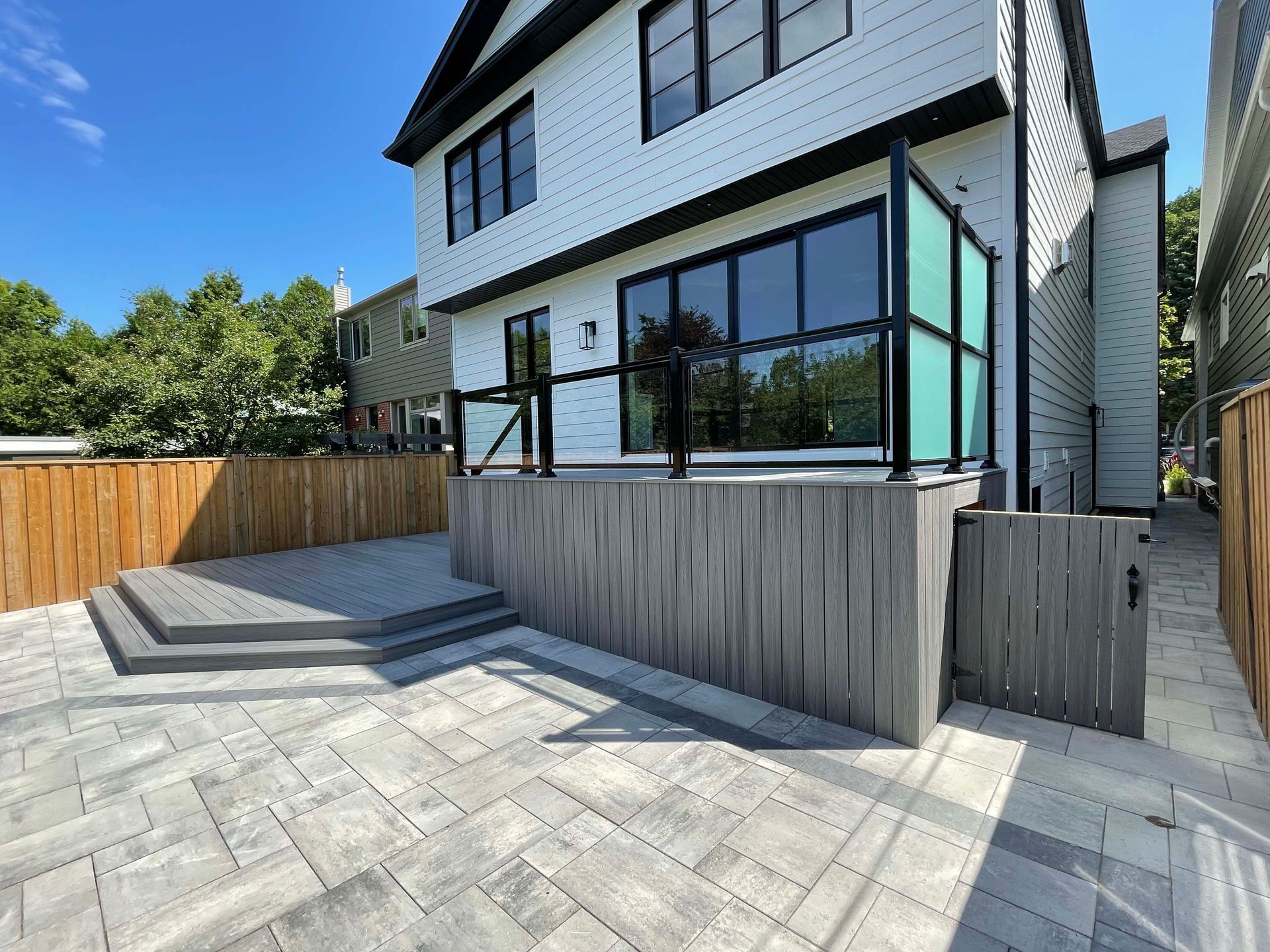 A large white house with a patio and a wooden fence in front of it.