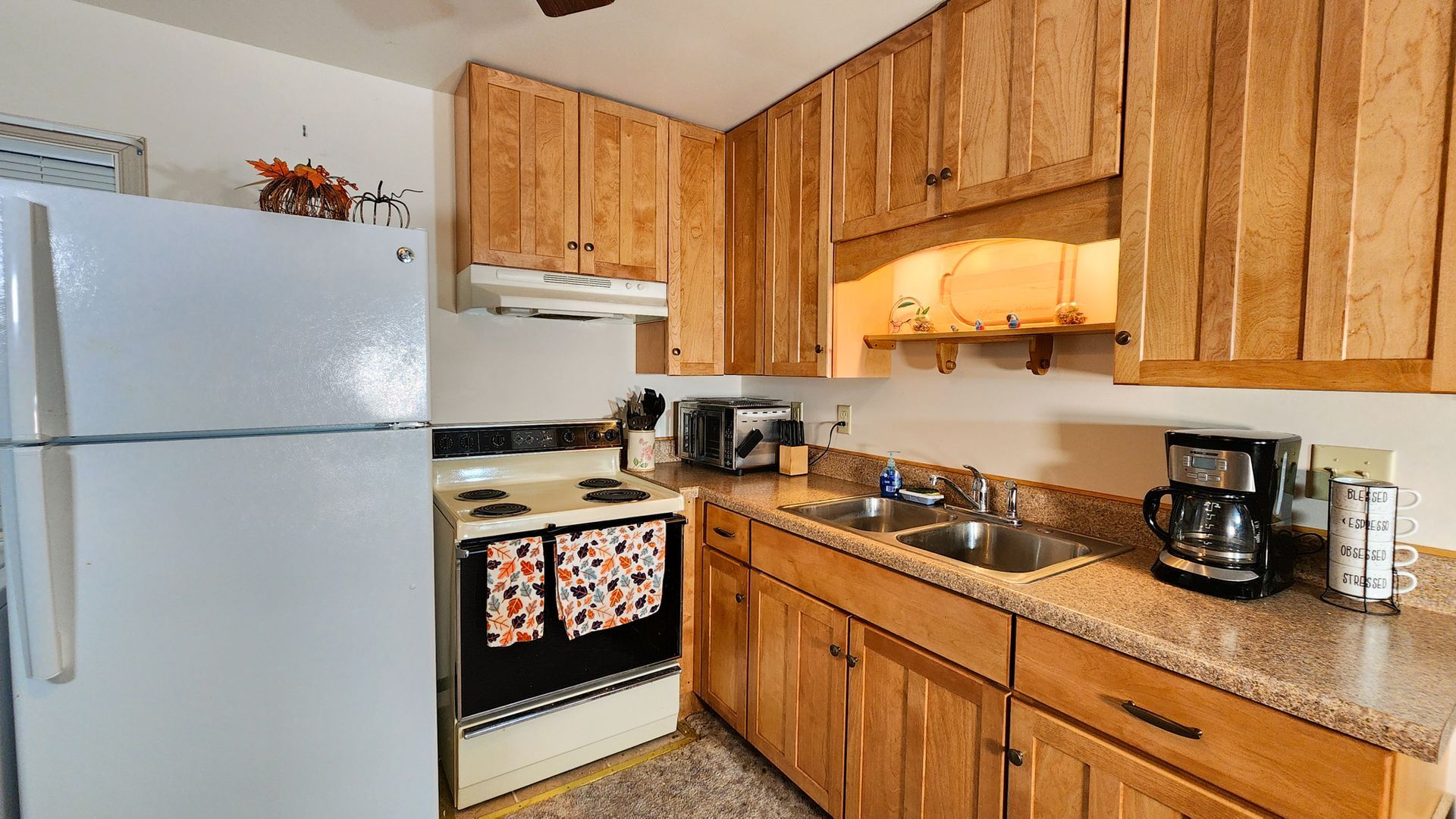 A kitchen with wooden cabinets , a white refrigerator , a stove and a sink.