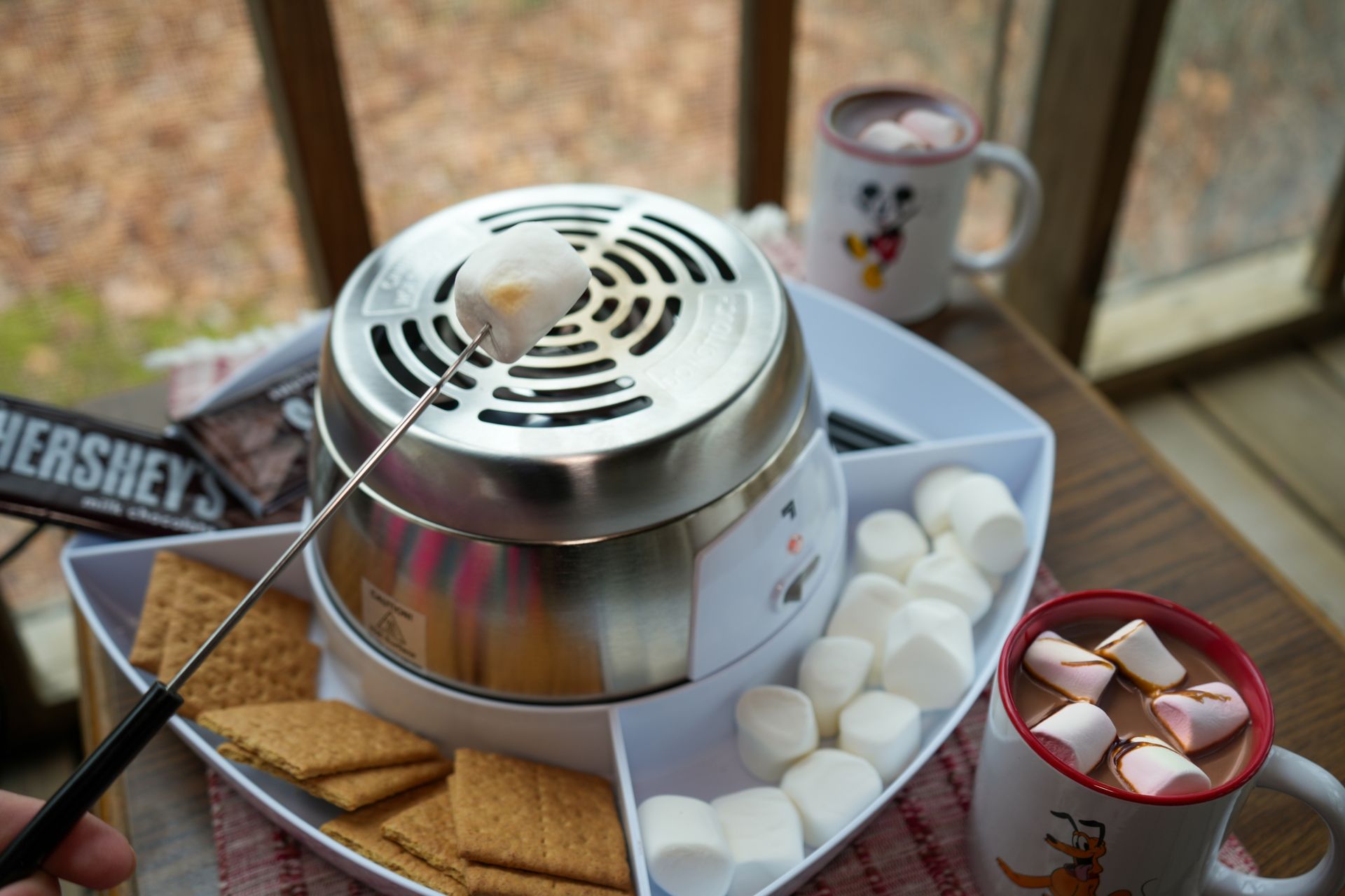 A person is roasting marshmallows in a fondue pot.