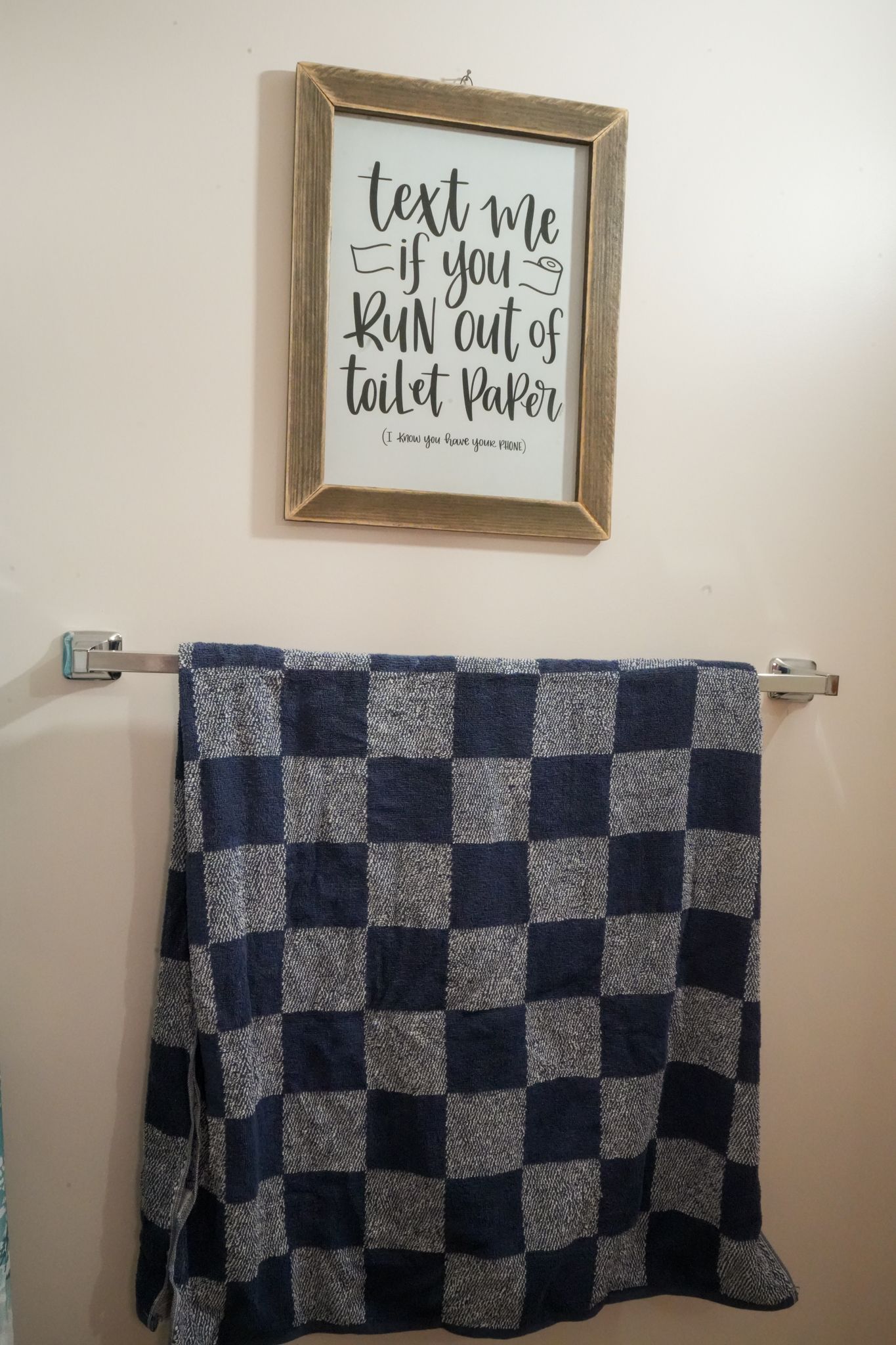 A blue and white checkered towel is hanging on a towel rack in a bathroom.