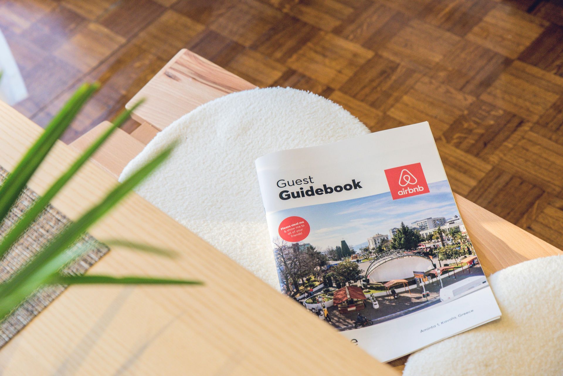 A guidebook is sitting on a wooden table next to a towel.