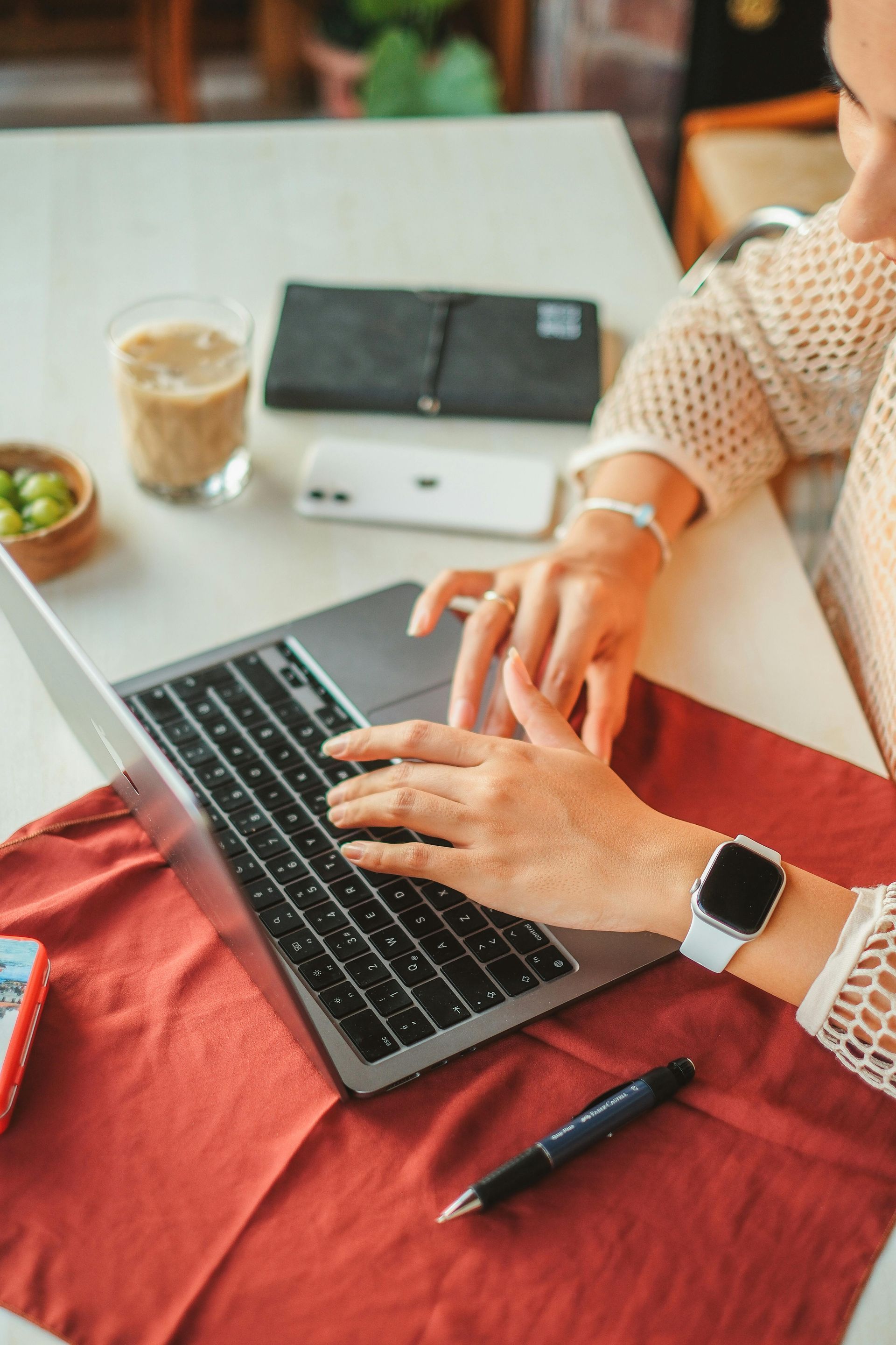 A woman is typing on a laptop computer at a table.