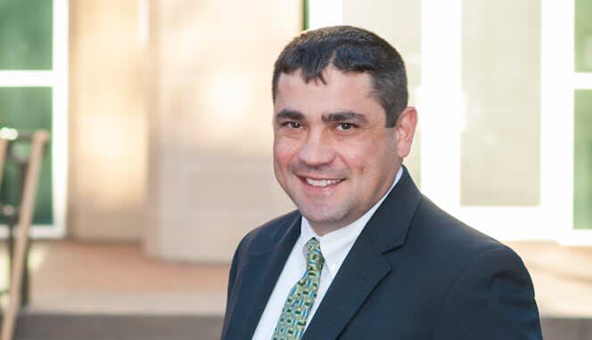 A man in a suit and tie is smiling for the camera.