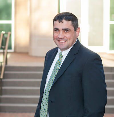 A man in a suit and tie is standing in front of stairs.