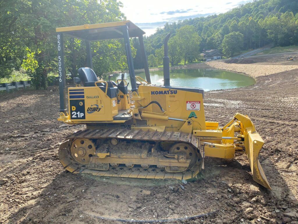 A yellow komatsu bulldozer is parked in a dirt field