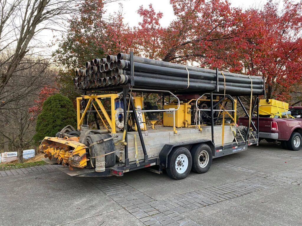 A truck is pulling a trailer with pipes on it.