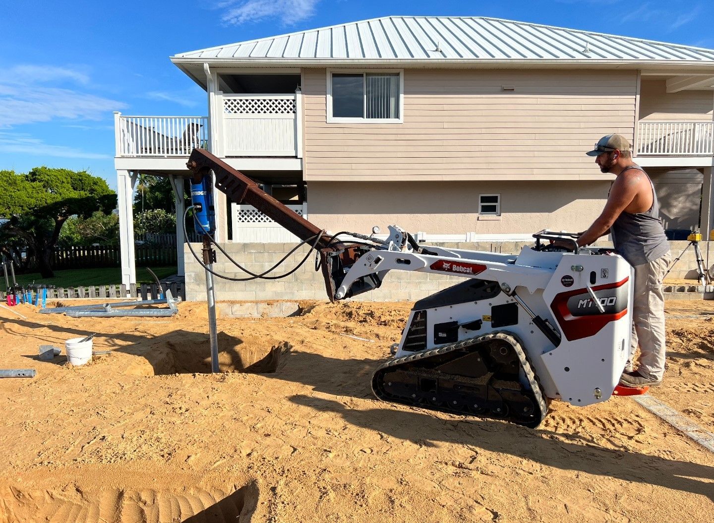 A man is working on a machine in front of a house