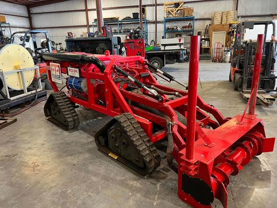 A red tractor is sitting on top of a dirt field.