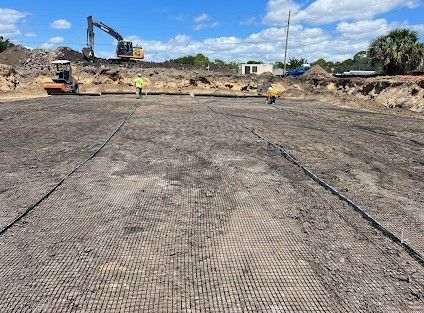 A construction site with a lot of dirt and a tractor in the background.