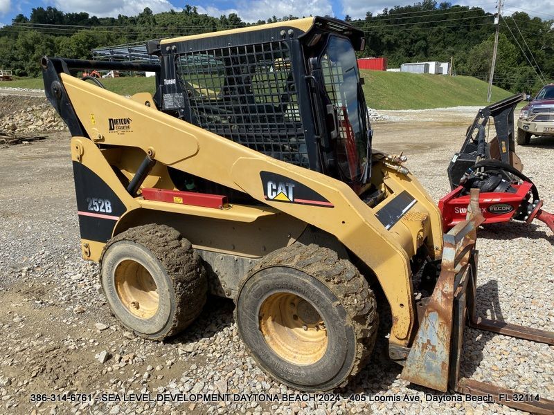 A cat skid steer is parked in a gravel lot