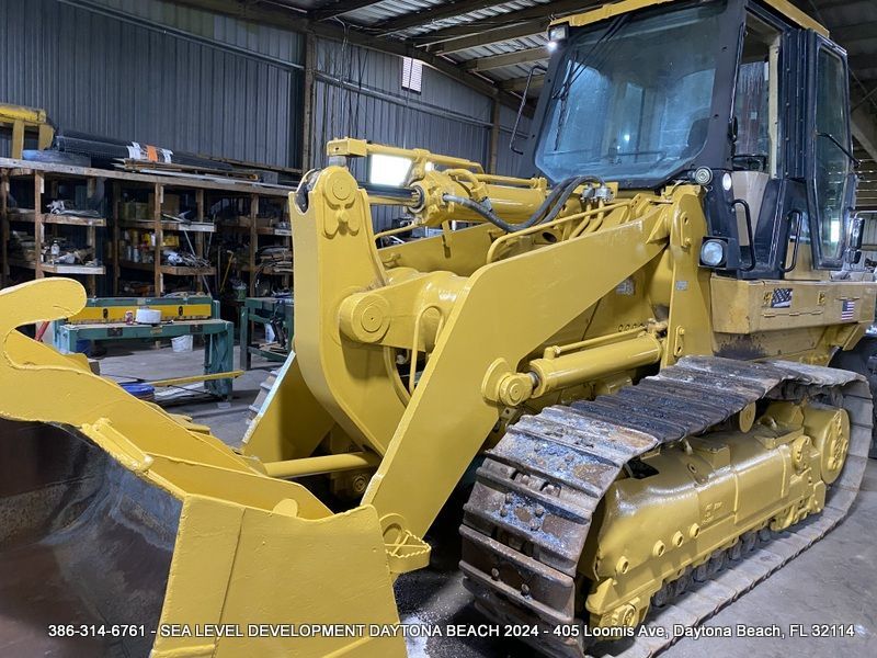 A yellow bulldozer is parked inside of a building