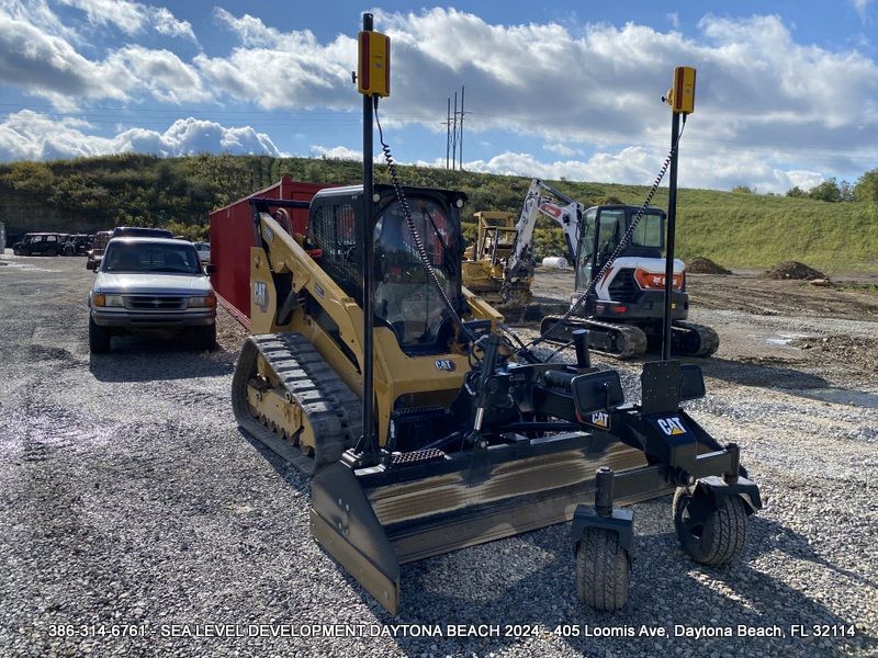 A bulldozer is parked in a gravel lot next to a white truck.