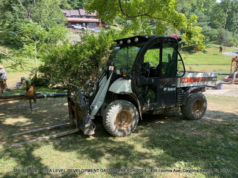 A vehicle with a forklift attached to it is parked in the grass.