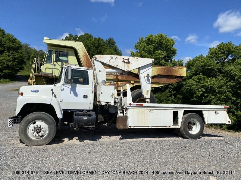 A white truck is parked next to a yellow dump truck