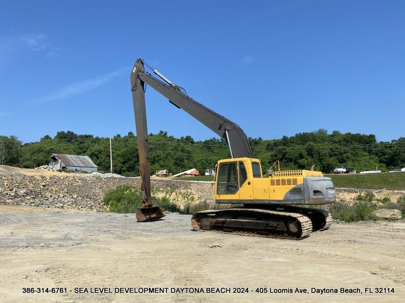 A large yellow excavator is parked in a dirt field
