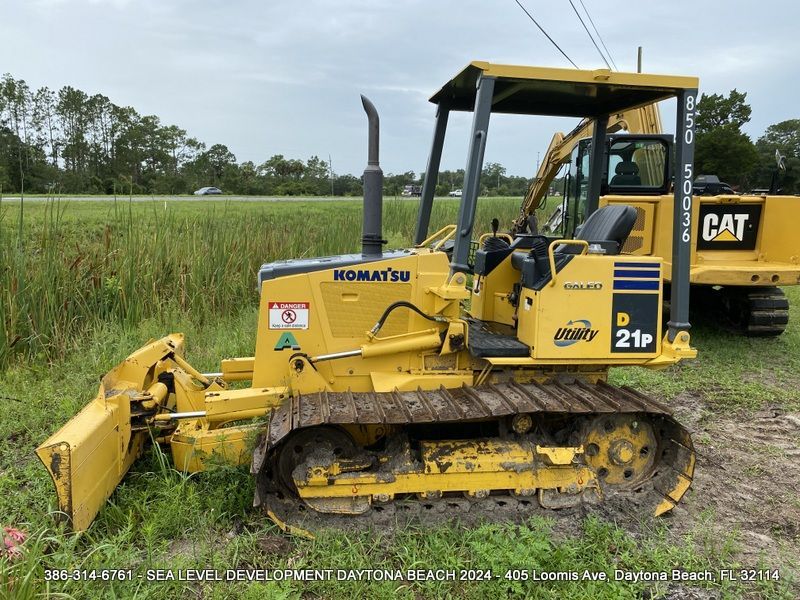 A yellow komatsu bulldozer is parked in a grassy field