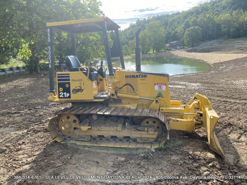 A yellow komatsu bulldozer is parked in a dirt field