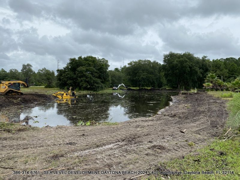 A large body of water with a yellow excavator in the middle of it.