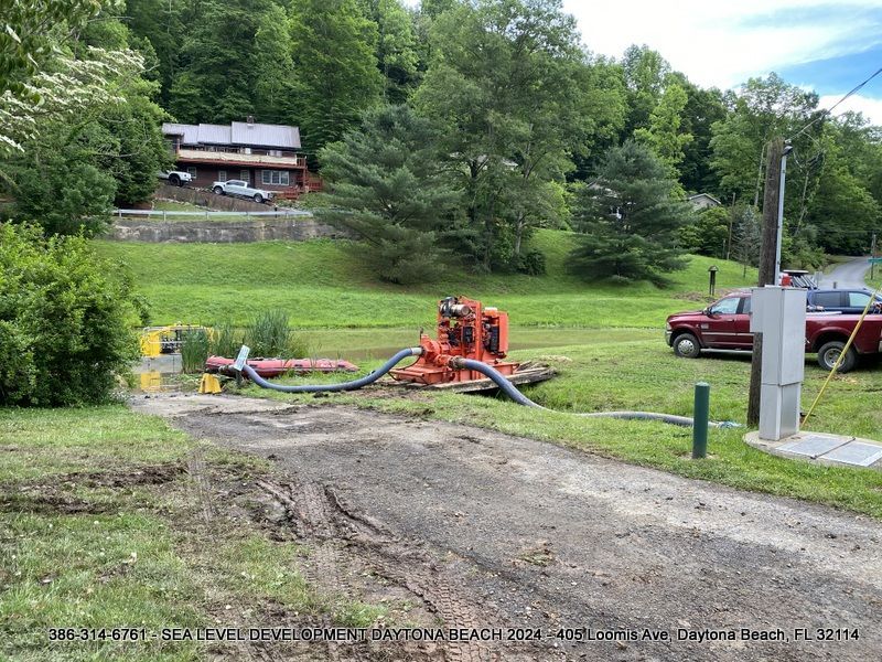 A red truck is parked on the side of a dirt road in a grassy field.