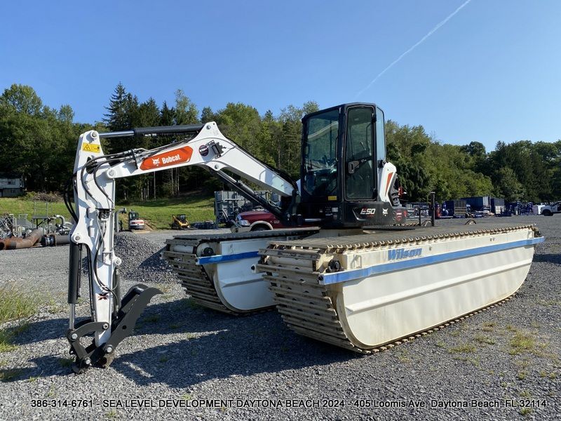 A bobcat amphibious excavator is parked in a gravel lot.