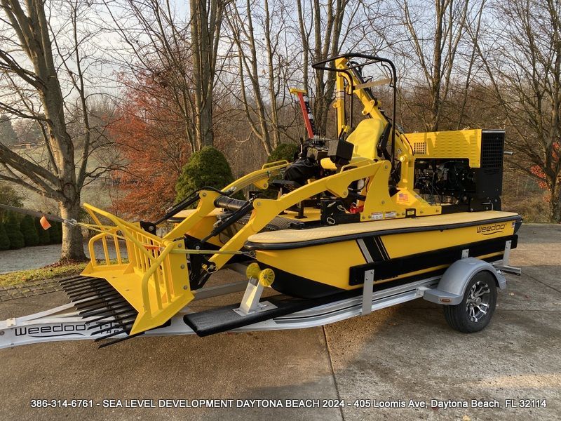 A yellow boat is on a trailer with trees in the background