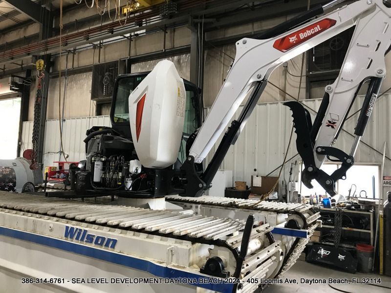 A bobcat excavator is sitting on a table in a garage.