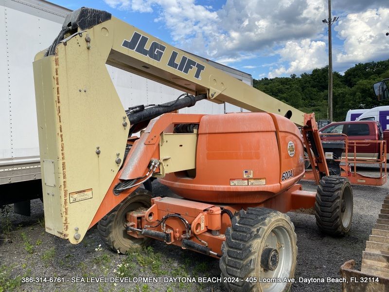 An orange jlg lift is parked in a parking lot