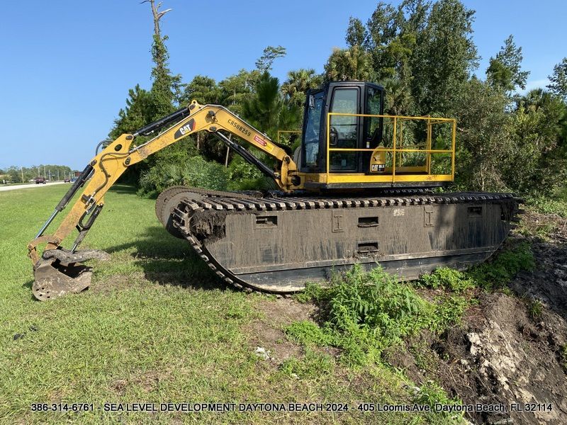 A large yellow excavator is parked in a grassy field