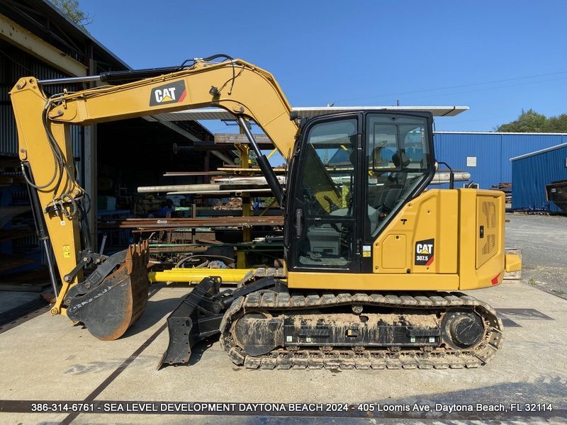 A yellow cat excavator is parked in front of a building