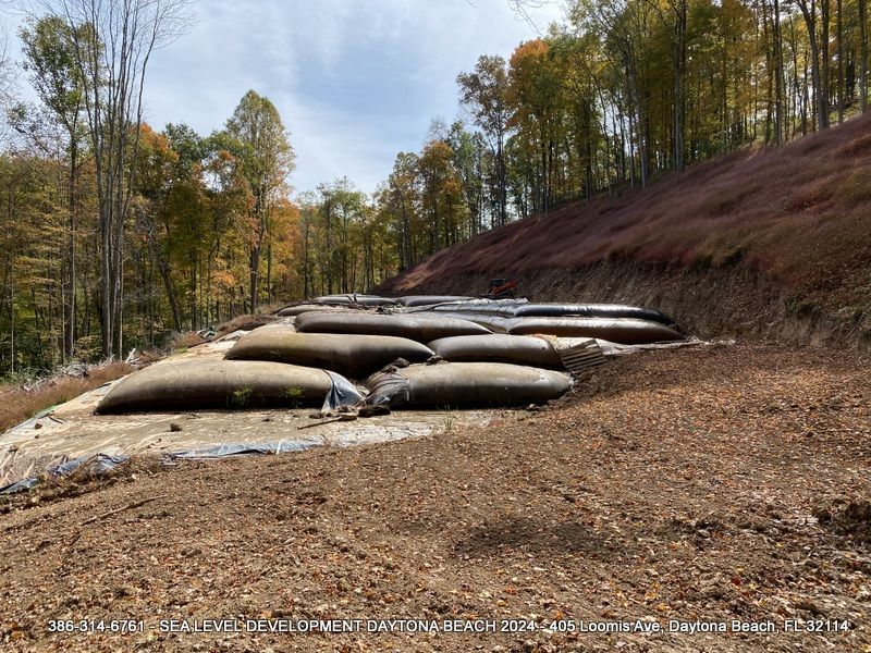 A pile of bags sitting on top of a dirt hill in the woods.
