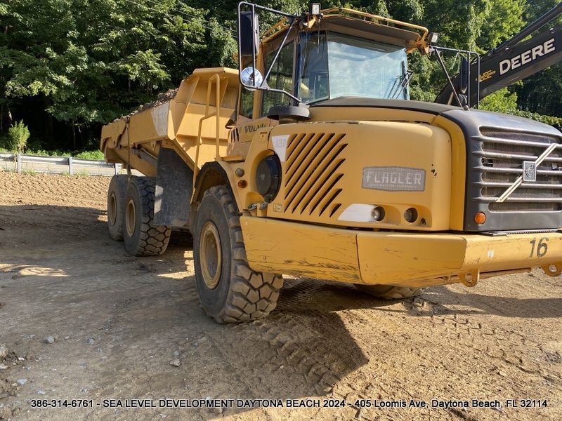 A volvo dump truck is parked in a dirt field