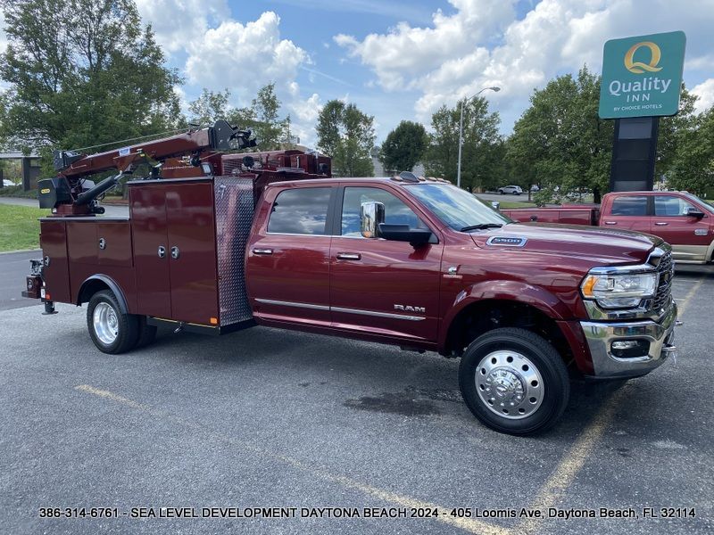 A red utility truck is parked in a parking lot next to a quality inn sign.