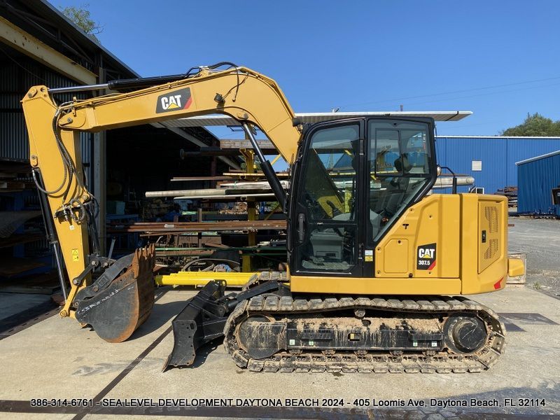 A yellow cat excavator is parked in front of a building