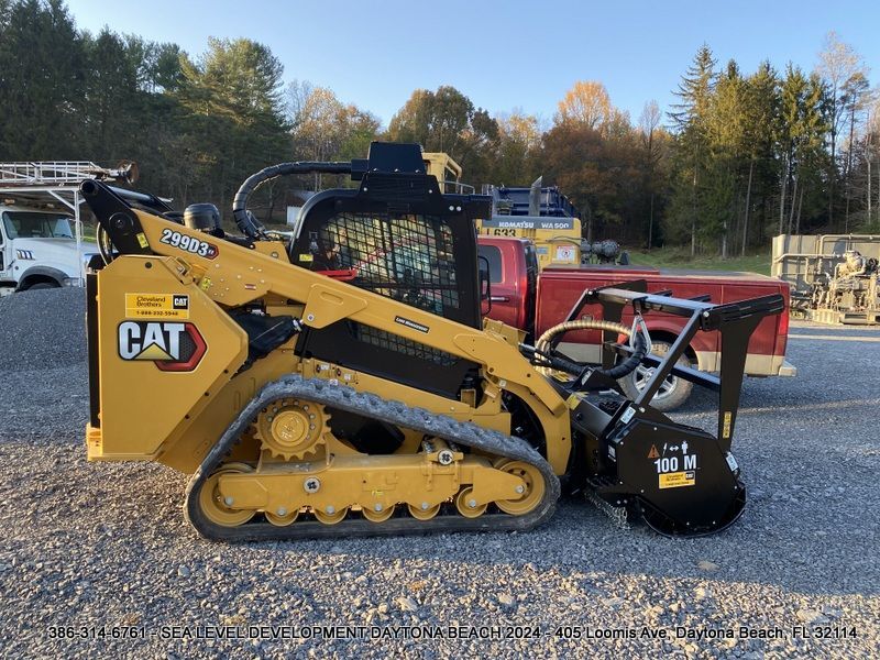 A yellow cat tractor is parked in a gravel lot