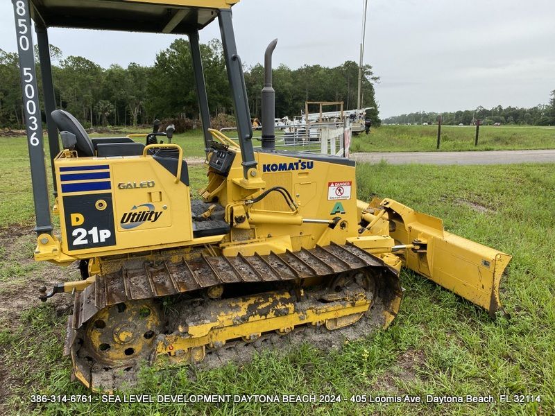 A yellow komatsu bulldozer is parked in a grassy field