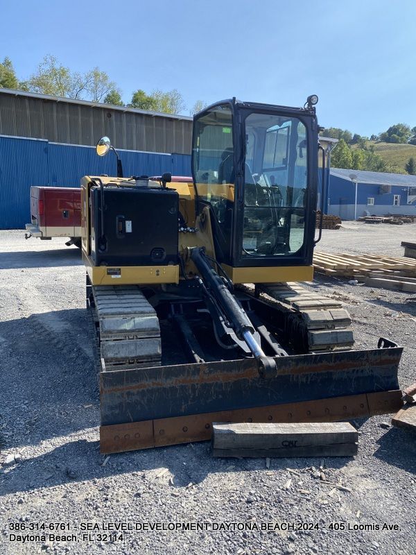 A bulldozer is parked in a gravel lot in front of a building.