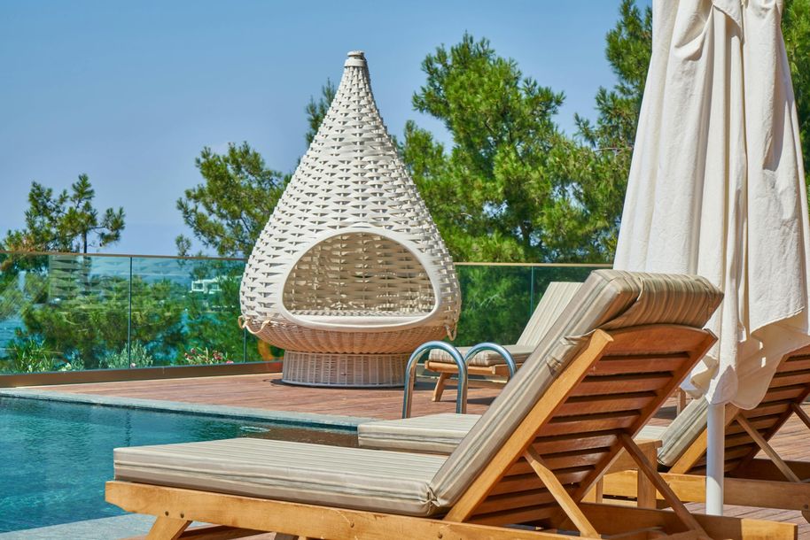 There are a lot of chairs and umbrellas around the pool.
