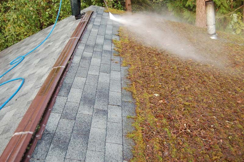 a person is spraying water on a roof with a hose .